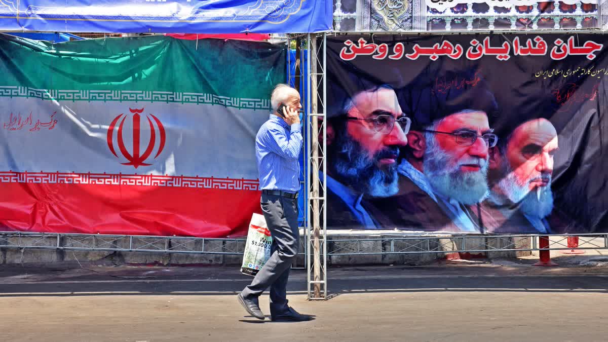 A man walks past Iran's national flag at the Vanak Square in Tehran