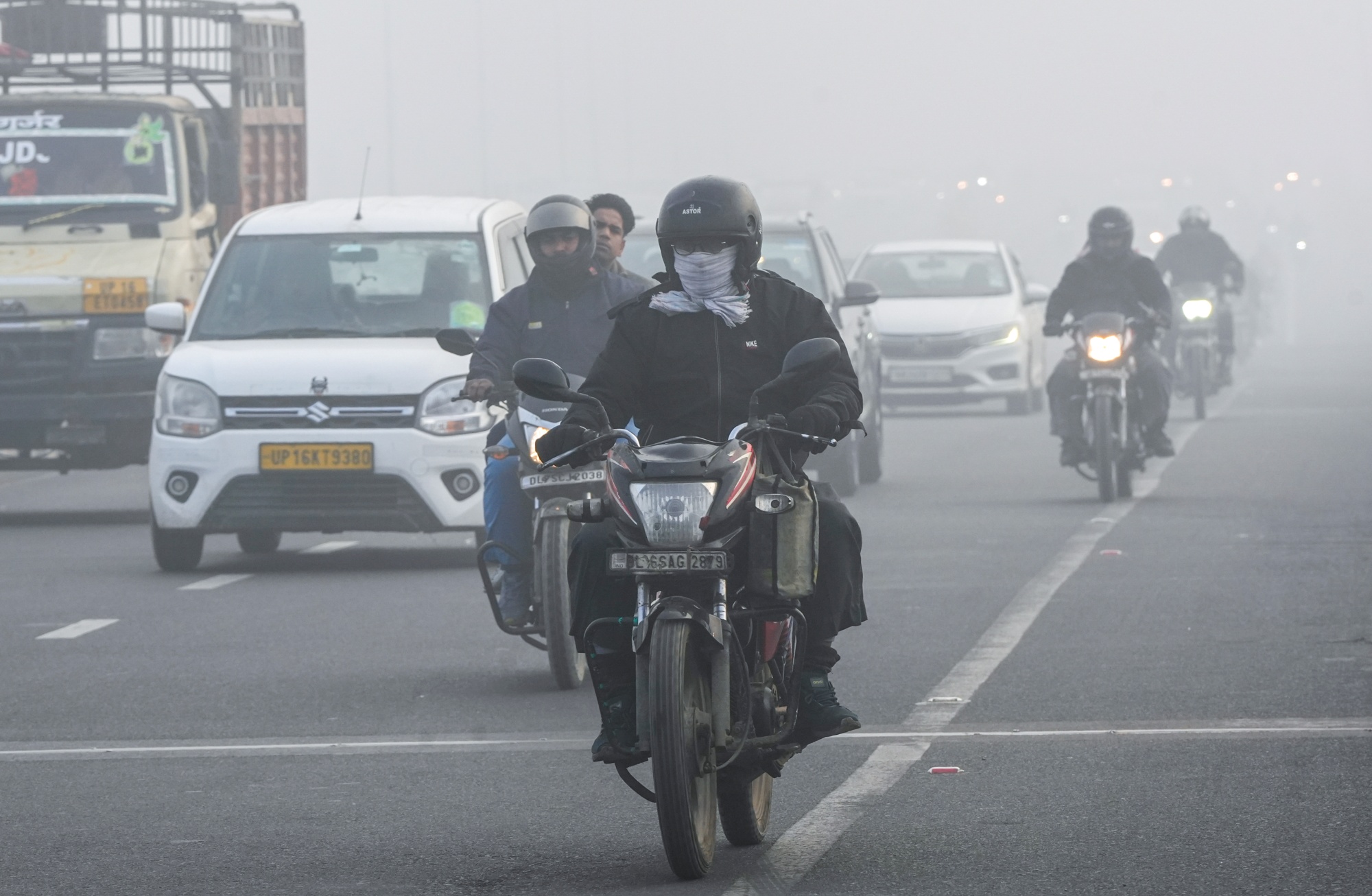 Vehicles move along a road amid fog on a cold winter morning, in New Delhi, Monday, Dec. 15, 2025.