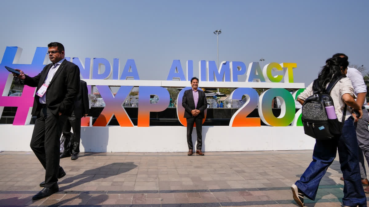 Visitors pose for photographs near the India AI Impact Summit 2026 signage at Bharat Mandapam, in New Delhi, Monday, Feb. 16, 2026.
