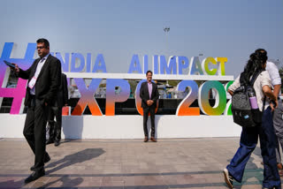 Visitors pose for photographs near the India AI Impact Summit 2026 signage at Bharat Mandapam, in New Delhi, Monday, Feb. 16, 2026.