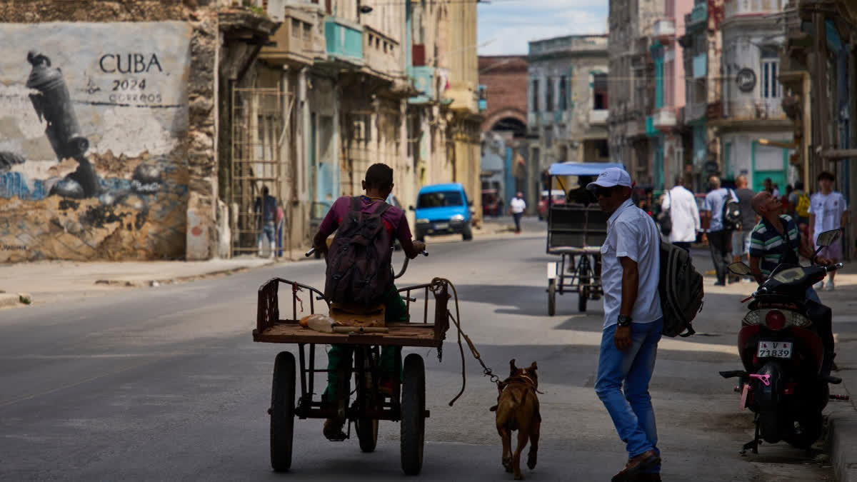 A man rides a tricycle with his leashed dog running alongside him during a blackout in Havana, Cuba, Monday, March 16, 2026.