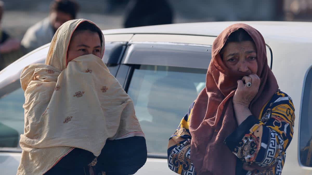 Two women watch as rescue workers and officials inspect the site of a late-Monday airstrike at a drug rehabilitation hospital in Kabul on Tuesday.