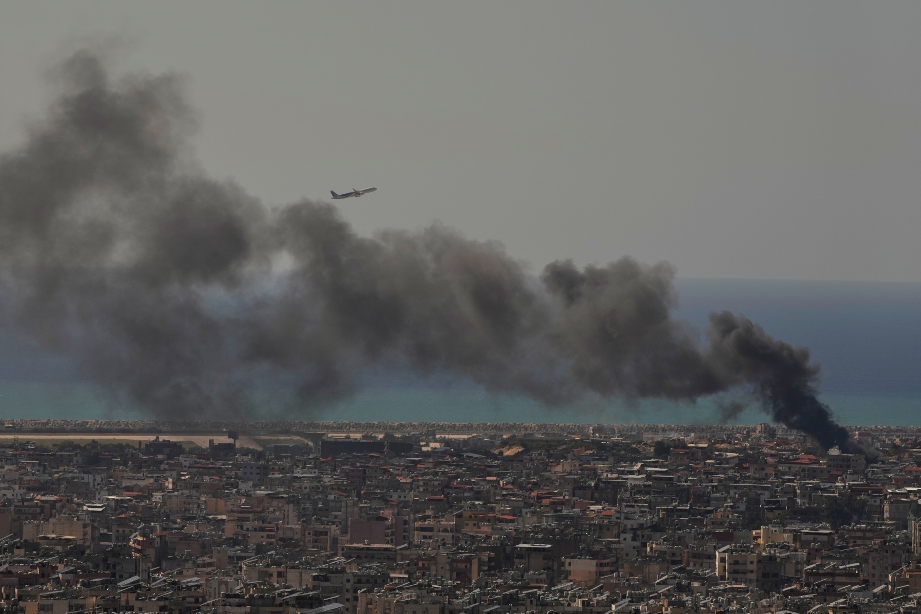 A Middle East Airlines plane takes off from Rafik Hariri International Airport as smoke rises from the site of an Israeli airstrike in Dahiyeh, Beirut's southern suburbs, Lebanon, Tuesday, March 17, 2026.
