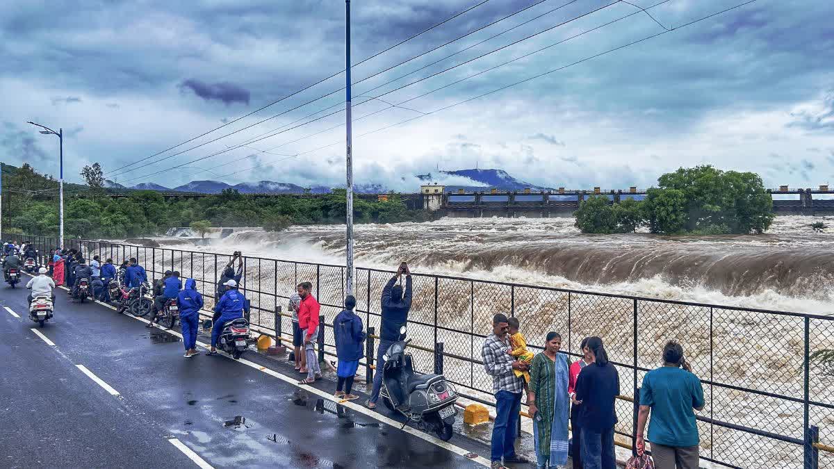 People in Pune watch the Mutha River in spate after water was released from the Khadakwasla Dam on July 8