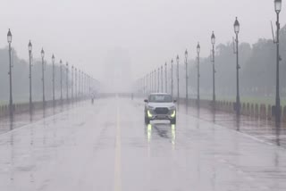 A vehicle makes its way through a rain-slicked road at Kartavya Path amid rainfall, in New Delhi on Wednesday.