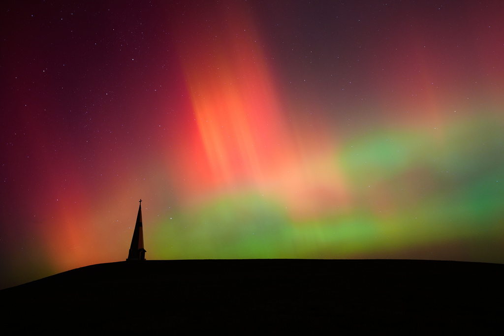 The northern lights fill the sky behind the Saint Joseph the Woodworker Shrine Tuesday, Nov. 11, 2025, near Valley Falls, Kan