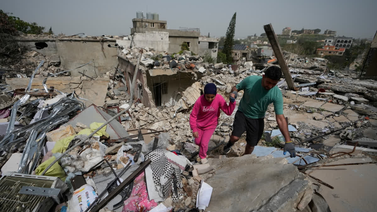 Residents walk on the rubble of destroyed houses on the second day of a ceasefire between Hezbollah and Israel in Jibchit village, south Lebanon, Saturday, April 18, 2026.