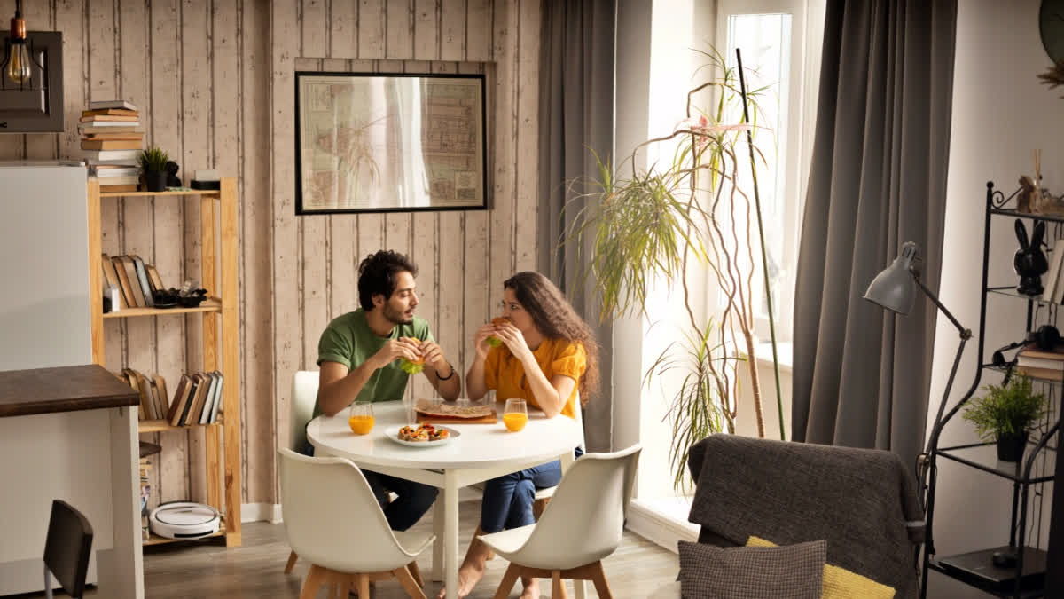 Dopamine Decor, Cluttercore And Mushrooms Were The Top Home Decor Trends Of 2024 Couple sitting inside a busy looking house