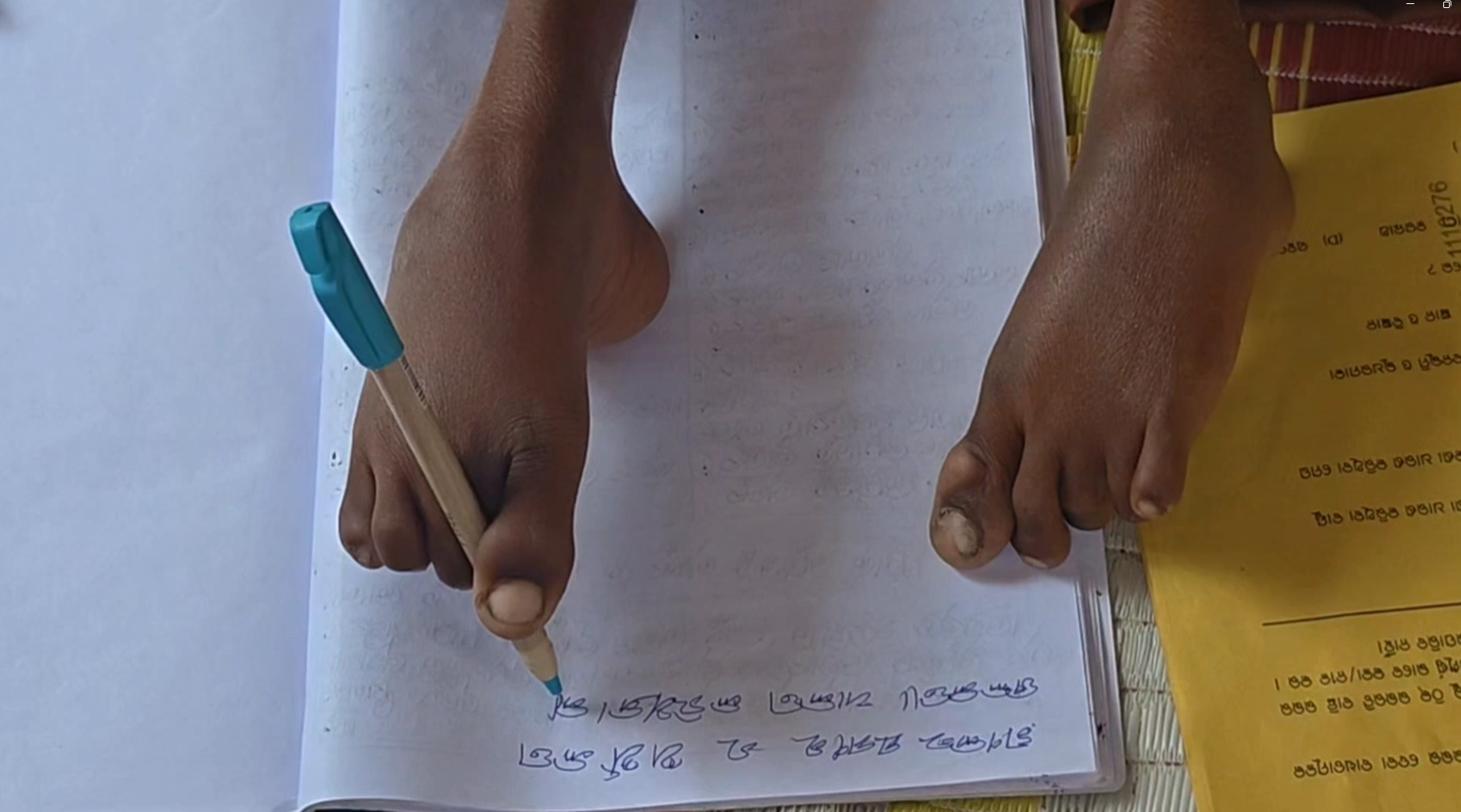 Lakshmi Khemudu is writing by foot.