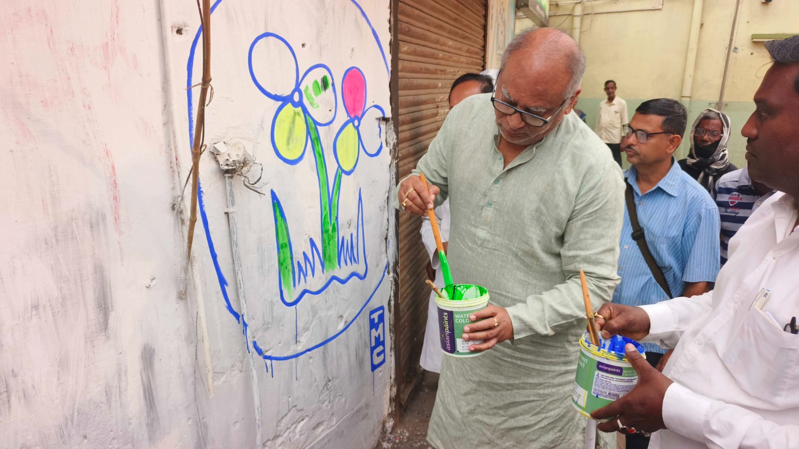 Chandranath Sinha, who has been nominated from Bolpur, writes a wall as part of the campaign.
