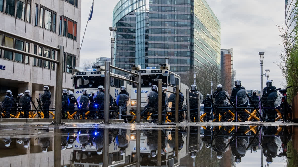 Police stand behind a barrier as European farmers block a road with their tractors during a demonstration outside the EU Summit in Brussels, Thursday, Dec. 18, 2025.