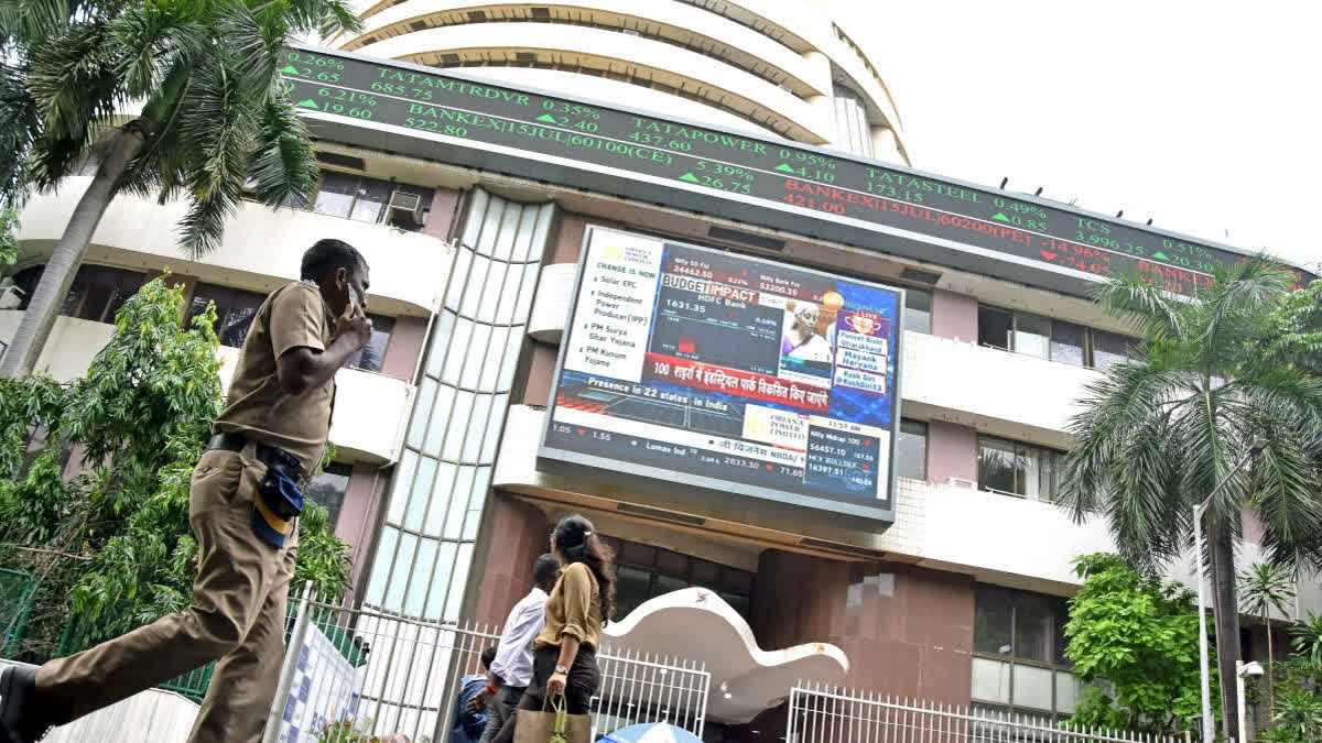 People walk past a display screen telecasting the Union Budget 2024-25 presentation by Union Finance Minister Nirmala Sitharaman at the Parliament House, outside the Bombay Stock Exchange (BSE) in Mumbai.