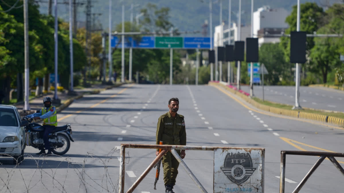 A police officer stands guard at a checkpoint on a barricaded road to ensure security ahead of the second round of the U.S. Iran officials talks, in Islamabad, Pakistan, Sunday, April 19, 2026.