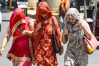 Commuters protect themselves from scorching heat while travelling along a road in Noida, Uttar Pradesh on Tuesday, May 19, 2026.