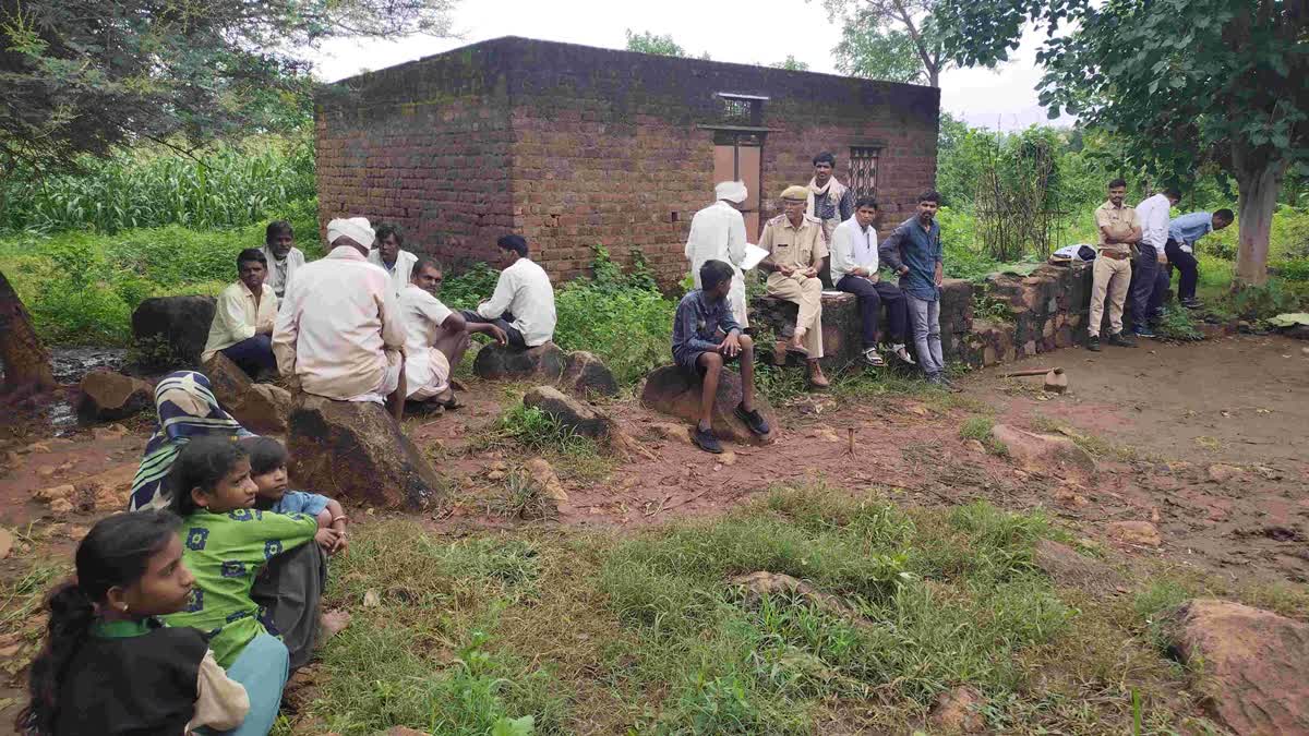 Cops and locals sit outside a house after double murder in Pratapgarh, Rajasthan