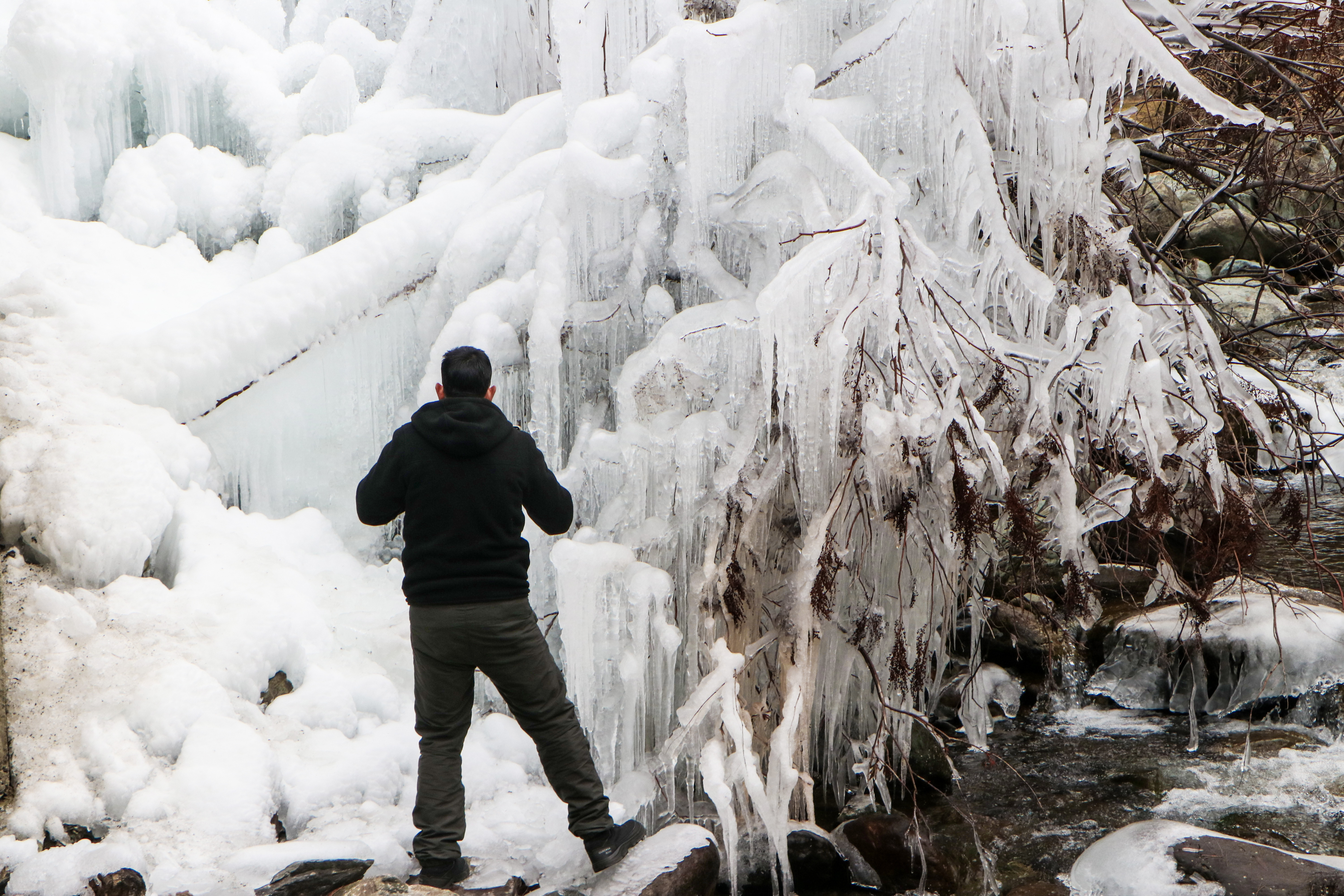 A man watches a frozen river amid sub-zero temperatures as severe cold conditions prevail in the region, in Anantnag, Kashmir