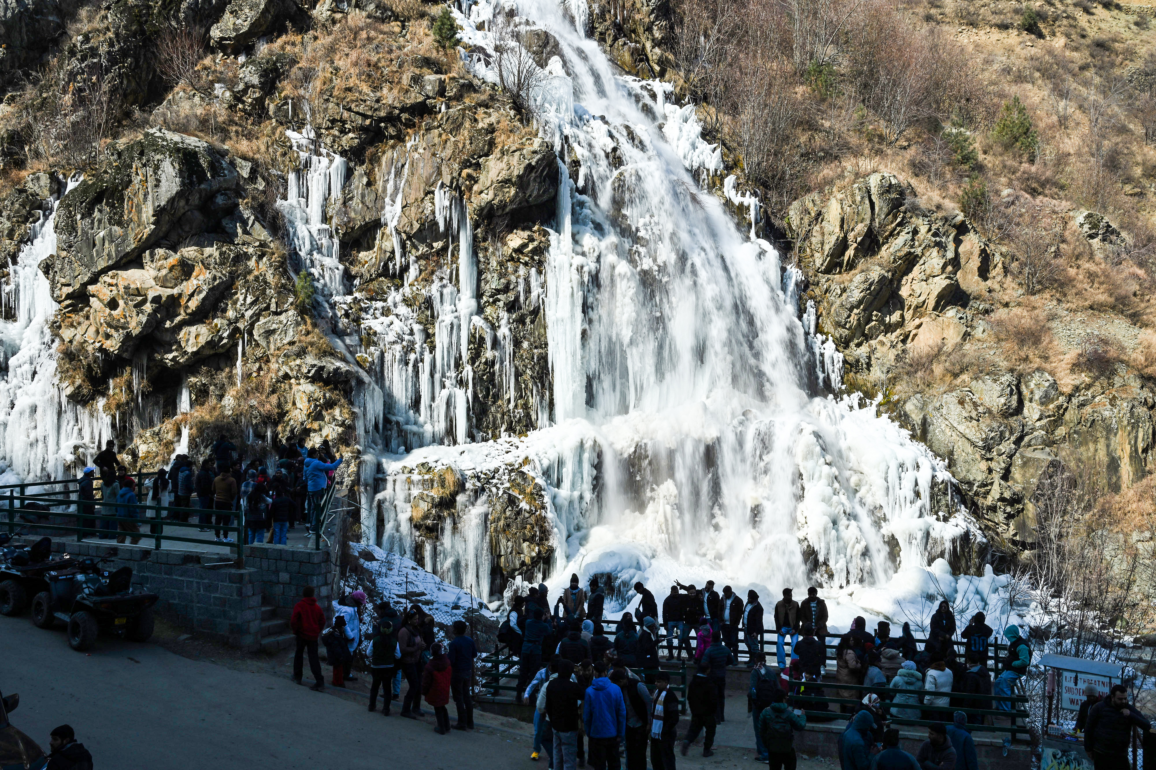 Tourists gather near a stream completely frozen at the Drung area of Tangmarg in Baramulla