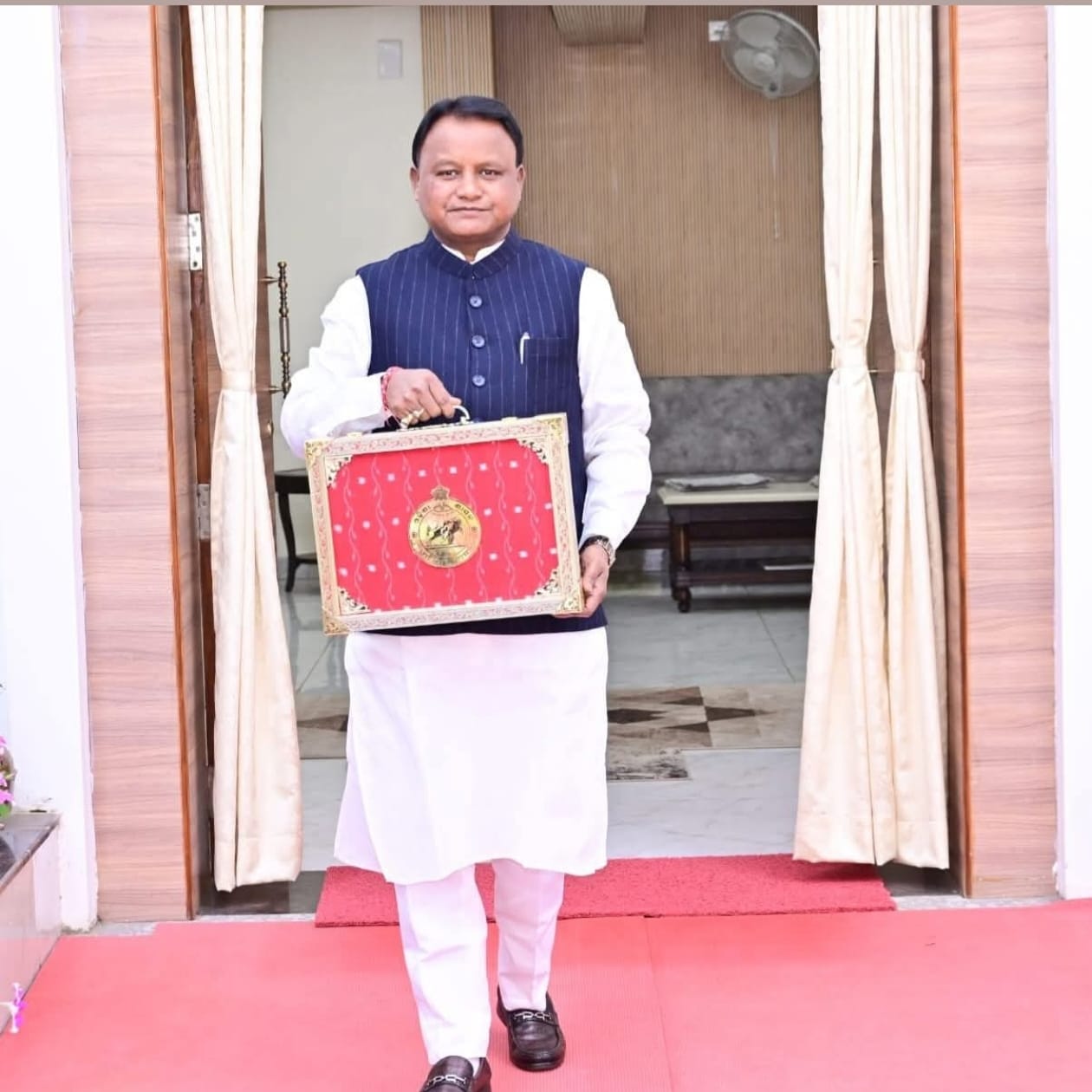 Mohan Charan Majhi holds a red suitcase.