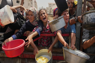 FILE - Palestinians struggle to get donated food at a community kitchen in Gaza City, northern Gaza Strip, Saturday, Aug. 16, 2025.