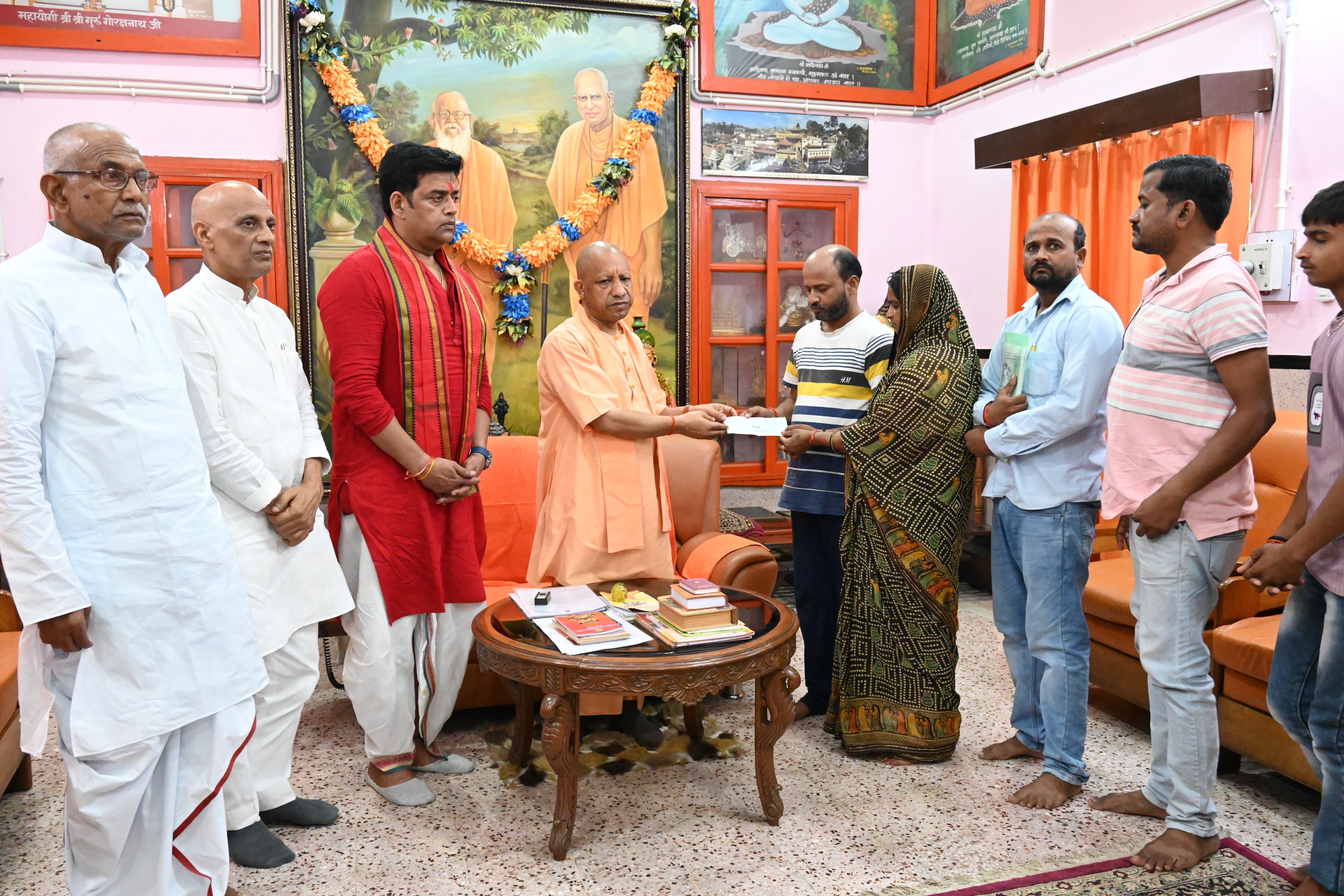 मारे गए नीट छात्र की परिजनों को चेक देते सीएम योगी आदित्यनाथ.
