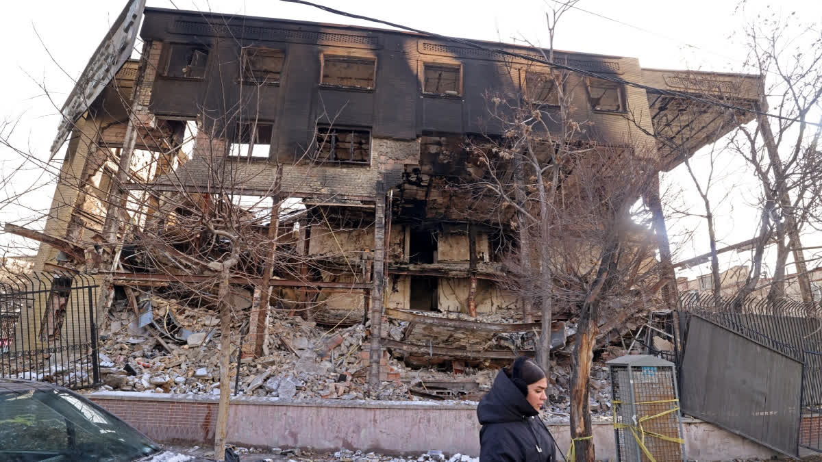 This photograph taken during a tour for foreign media shows a woman walking past a government building that was burnt during recent public protests, in Tehran on January 21,
