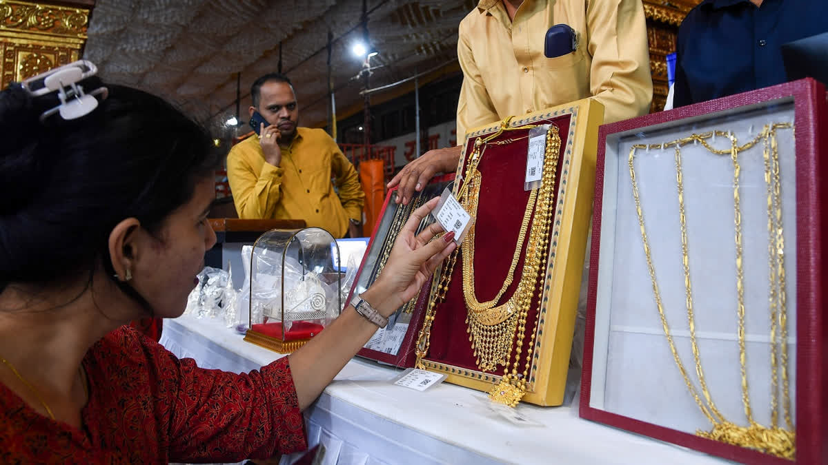 A woman looks at a gold jewellery piece during an open auction of gold and silver items offered by devotees at the feet of Lalbaugcha Raja during the Ganesh festival in Mumbai on Thursday, September 11, 2025.