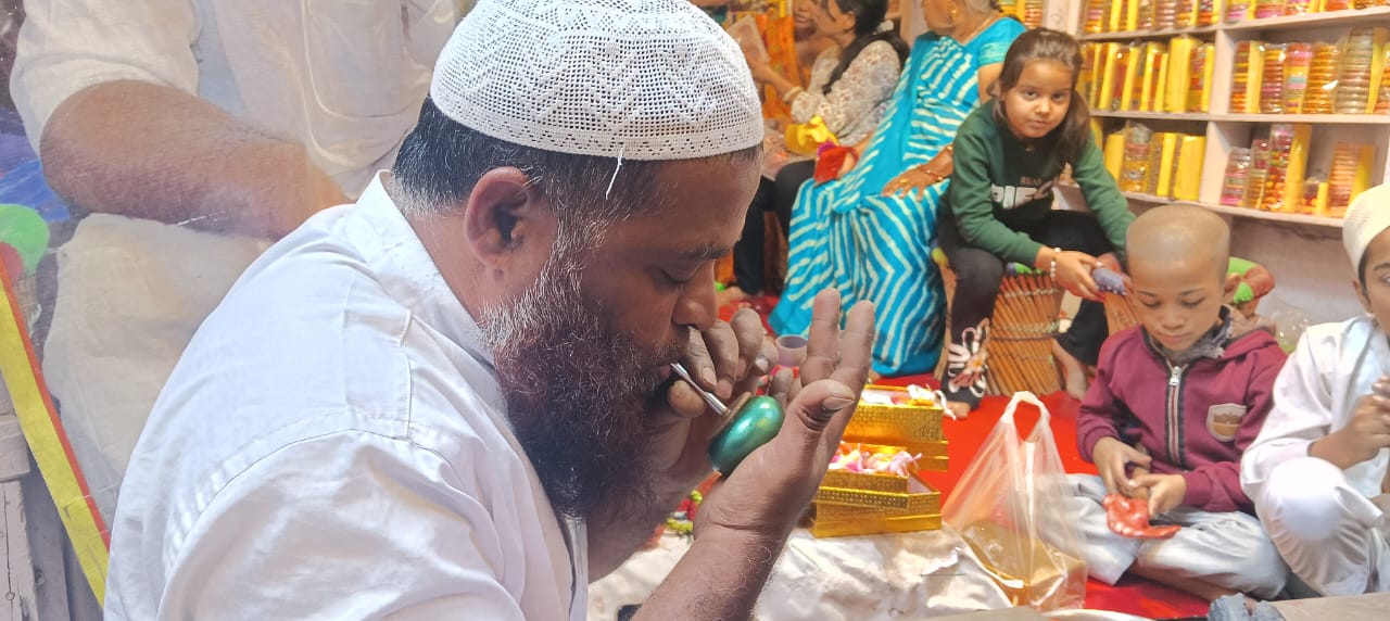 गुलाल गोटे को फुकनी की सहायता से मुंह से फुलाकर तैयार करते कारीगर