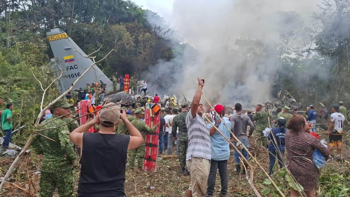 People stand around a military cargo plane that crashed after taking off from Puerto Leguizamo, Colombia, a remote municipality in the Amazonian province of Putumayo, Monday, March 23, 2026.