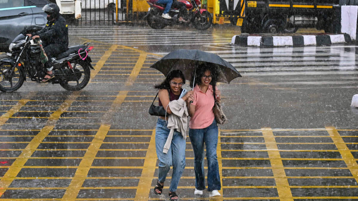 People walk under an umbrella during rainfall, in Mumbai, Maharashtra.