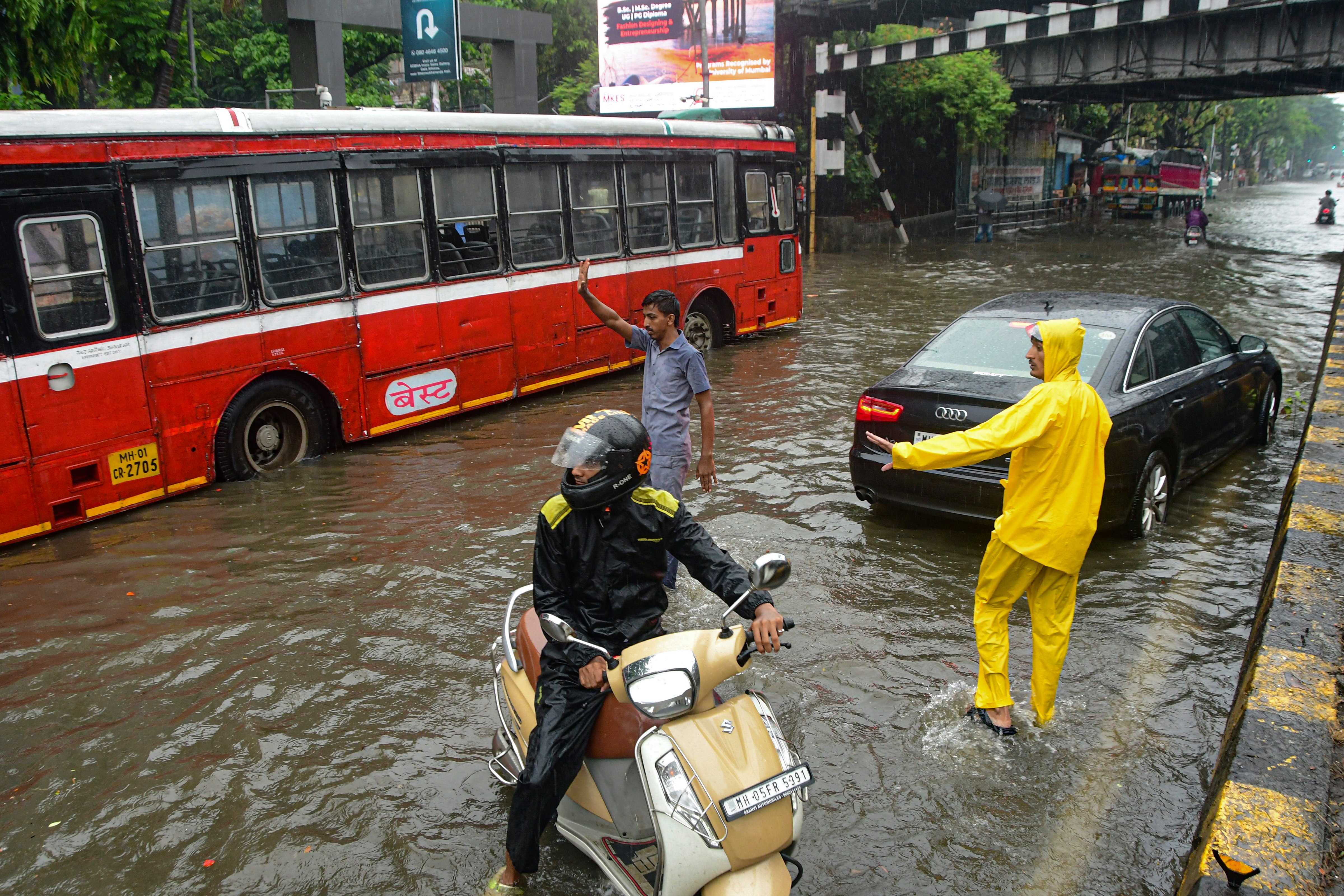 Commuters wade through a waterlogged road after heavy rainfall, in Mumbai, Maharashtra.