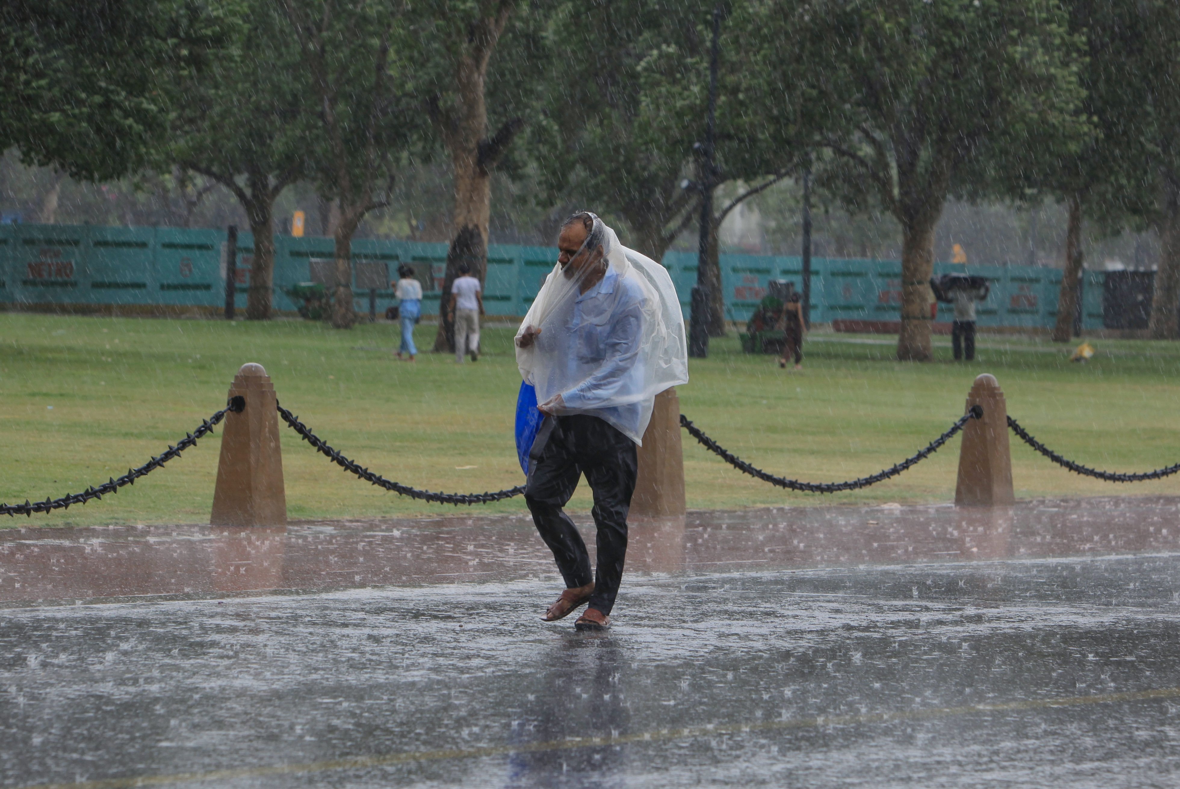 A man covers himself with a raincoat amid rain at Kartavya Path, in New Delhi on Tuesday.
