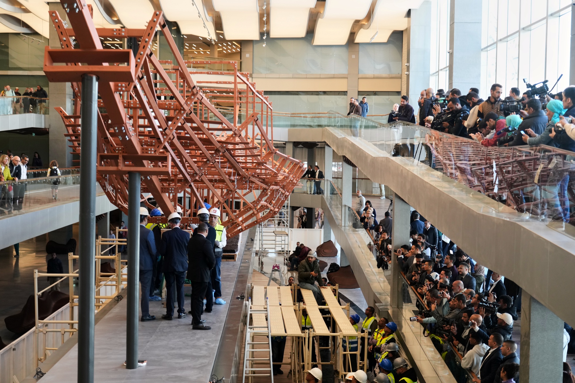 People film archeologists as they reassemble the second solar boat of King Khufu, at the Grand Egyptian Museum in Giza, Egypt, Tuesday, Dec. 23, 2025.