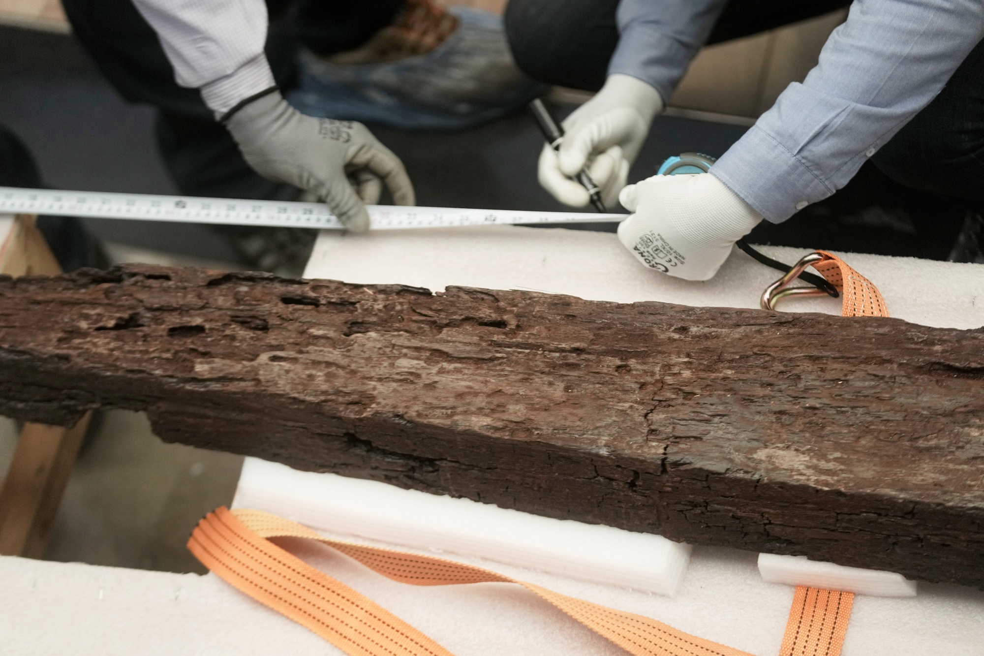 Archeologists measure an ancient wooden block as they prepare to reassemble the second solar boat of King Khufu, at the Grand Egyptian Museum in Giza, Egypt, Tuesday, Dec. 23, 2025.