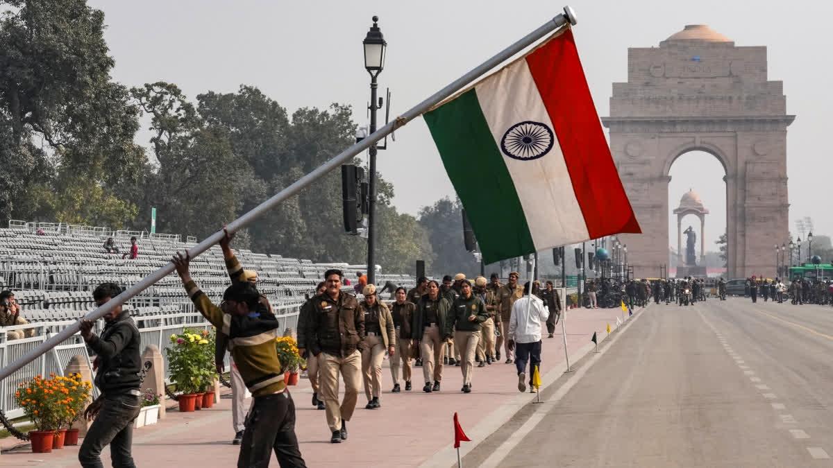 New Delhi: Workers raise a pole bearing the Indian national flag as police personnel look on during rehearsals for the Republic Day Parade, near the India Gate, in New Delhi, Wednesday, Jan. 21, 2026.