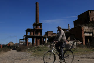 A man rides a bicycle near the ruins of the metallurgical plant in Elbasan, on March 7, 2025.