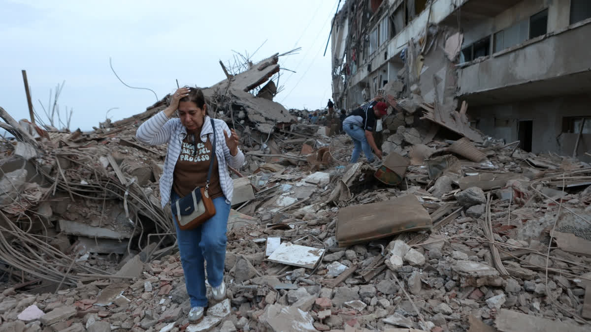 Residents walk among the rubble of building damaged in earthquakes the previous day in Catia La Mar, Venezuela, Thursday, June 25, 2026.