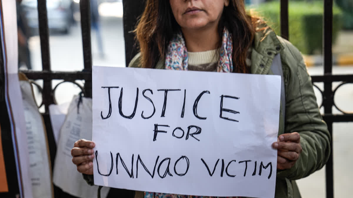 A protester holds a placard during a demonstration against the suspension of the jail term of Kuldeep Sengar, a former BJP MLA who was convicted in the Unnao rape case, outside the Delhi High Court, in New Delhi, Friday, Dec. 26, 2025.