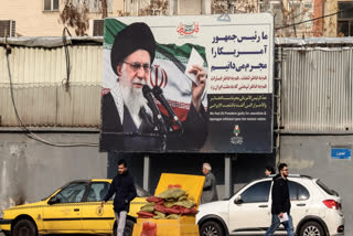 Iranians walk past a billboard showing Iranian supreme leader Ayatollah Ali Khamenei with anti-US rhetoric in Tehran