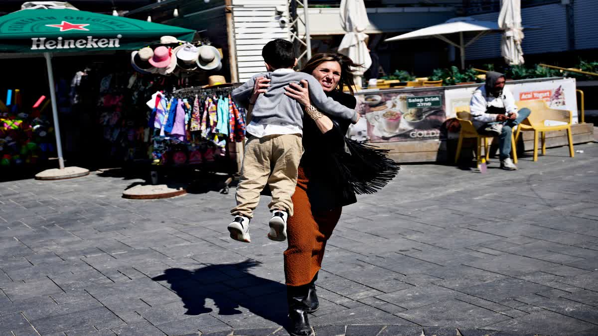 A woman flees with her child after Iran attacks Israel