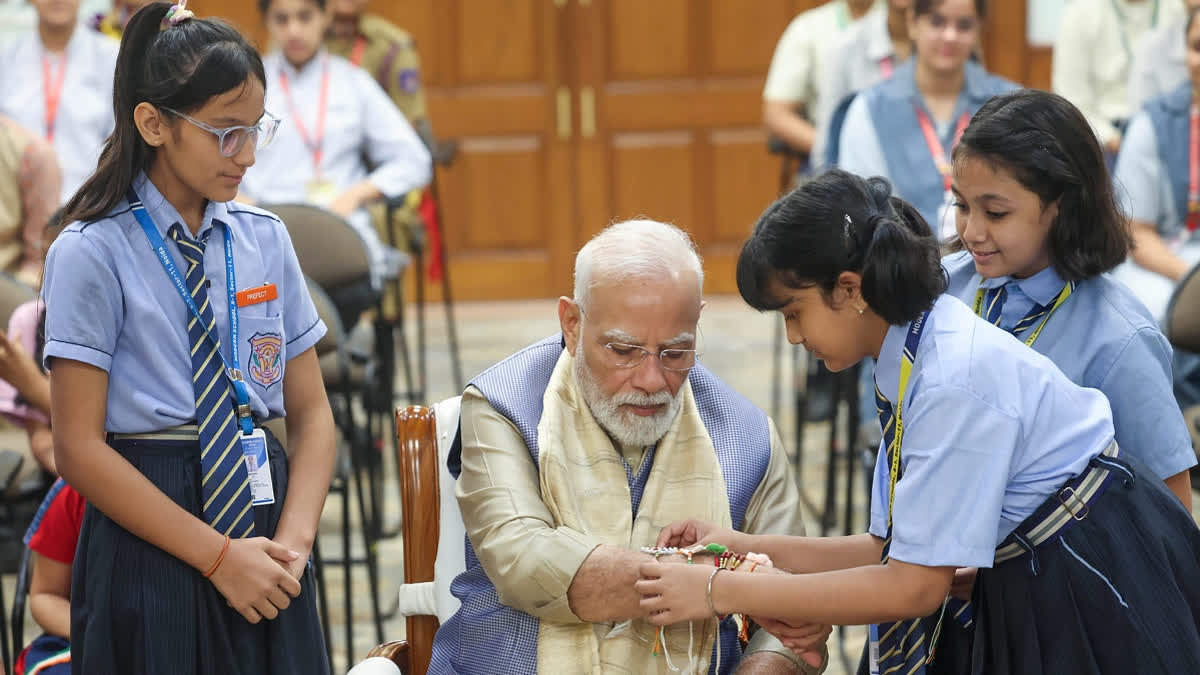 A school child ties a 'Rakhi' to Prime Minister Narendra Modi during the 'Raksha Bandhan' celebrations, in New Delhi on Friday.