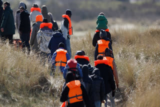 Migrants trying to reach Britain, walk on a beach shore in Gravelines, northern France, Wednesday, March 18, 2026.