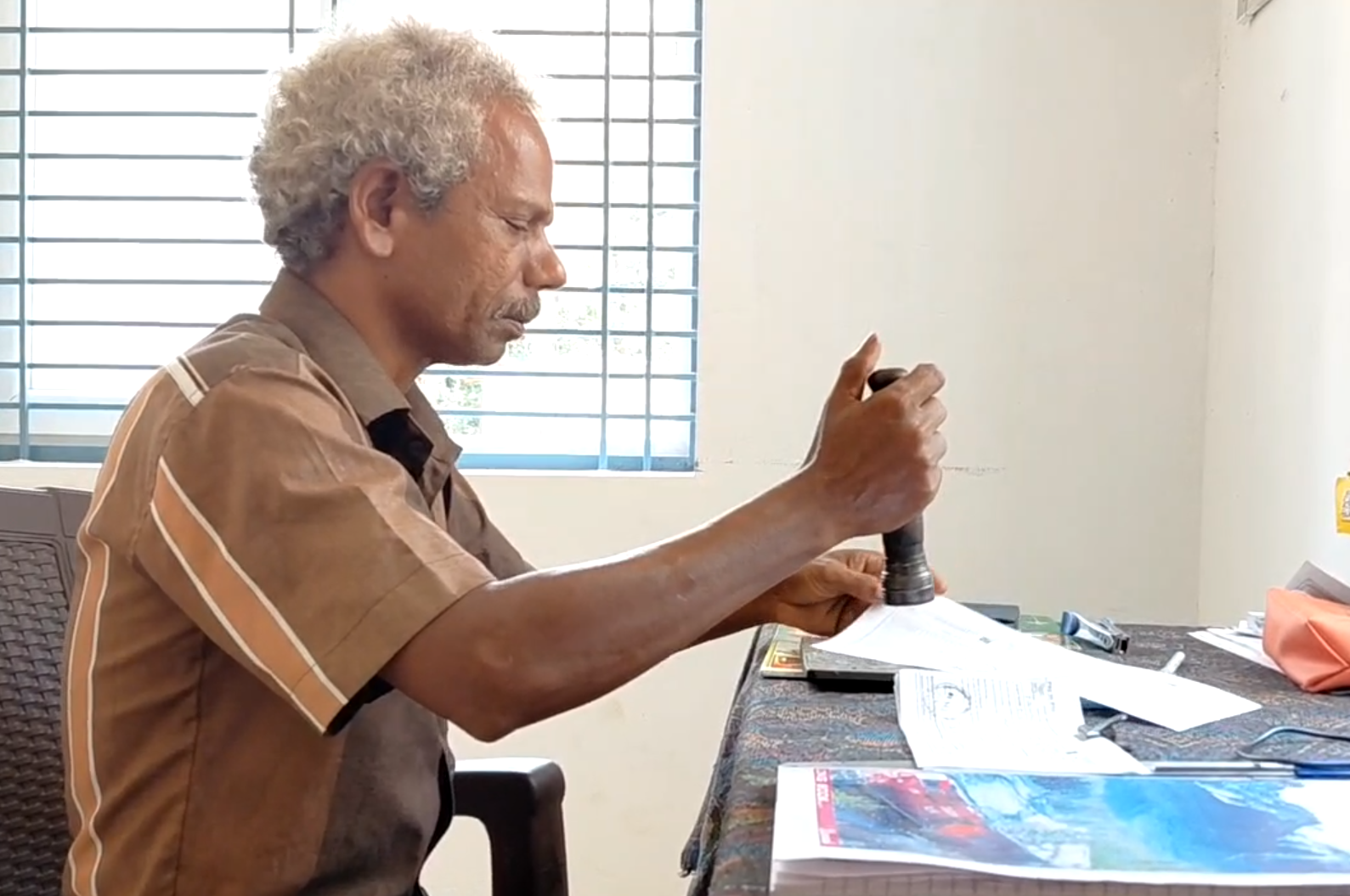 இணையதள சேவைக்காக சமுதாய நலக்கூடத்தில் அமர்ந்து அஞ்சலக பணியை செய்யும் ஊழியர்