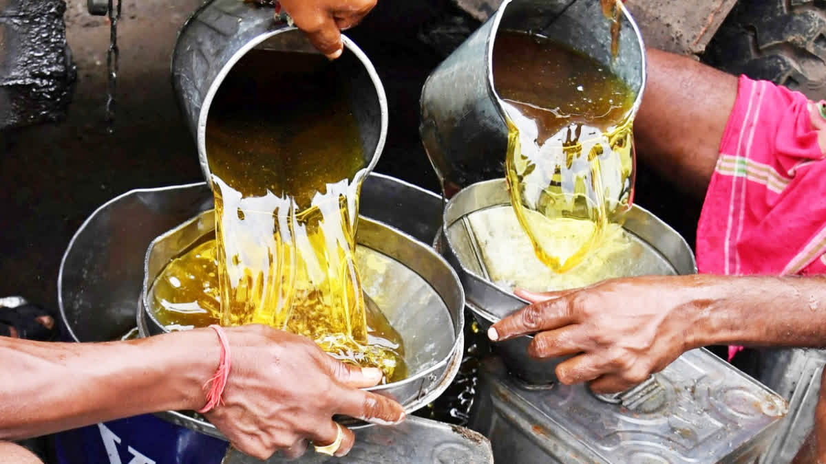 Indian labourers fill up edible oil from a tanker into other small containors for transportation at a wholesale market in Kolkata on June 29, 2017