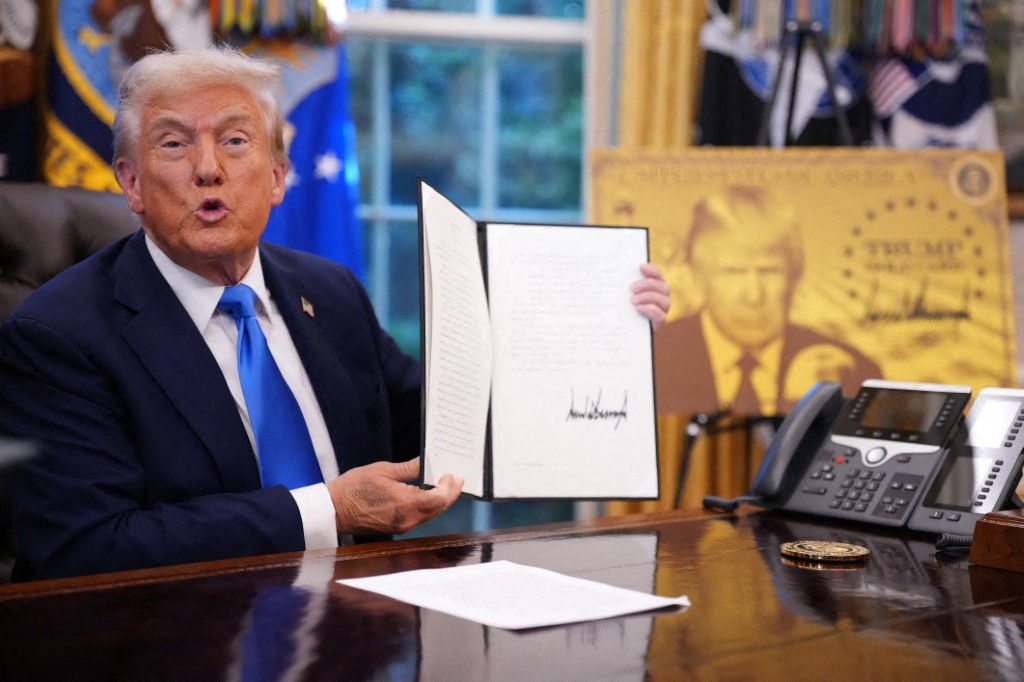 President Donald Trump holds up an executive order establishing the 