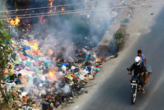 A heap of garbage is set on fire as commuters pass by at Kanakapura Link Road in Thagachaguppe village, causing air pollution and inconvenience to the public in Bengaluru, Karnataka, on Saturday, January 24, 2026.