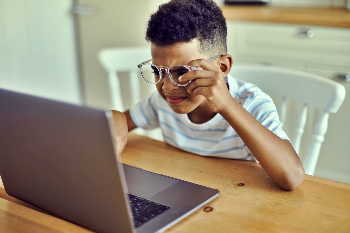 Young boy squinting at the laptop