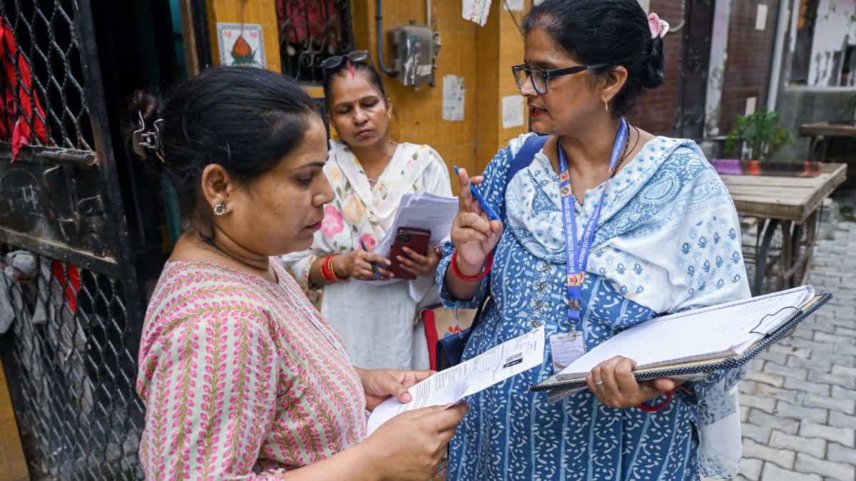 A Booth Level Officer (BLO) verifies voter details and updates electoral records during a door-to-door voter verification drive, in New Delhi.